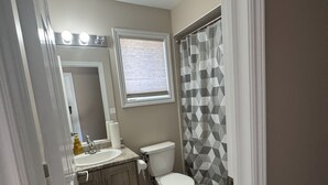 A bathroom with a toilet, sink, mirror, and shower curtain.
