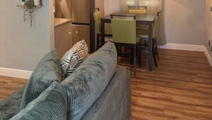 A compact living space with a sofa, a dining table with chairs, a refrigerator, and wall-mounted shelves with plants. - Amelias Arena Retreat 4bedroom home in Orlando (Orlando)