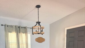 A dining area with a dark wooden table, four chairs with yellow upholstery, a hanging light fixture, and a 'WELCOME' sign on the wall. - Amelias Arena Retreat 4bedroom home in Orlando (Orlando)