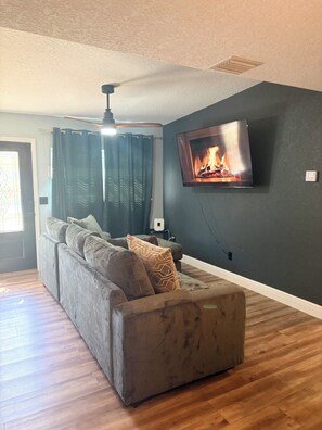 A living room with a sofa, a television mounted on the wall, and a ceiling fan. - Amelias Arena Retreat 4bedroom home in Orlando (Orlando)