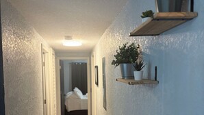 A hallway with wooden flooring, a ceiling light, and wall-mounted shelves with plants. - Amelias Arena Retreat 4bedroom home in Orlando (Orlando)
