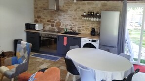 Una cocina con paredes de piedra, una mesa de comedor con sillas, un sofá y lámparas colgantes.