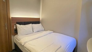 A hotel room with a bed, a wooden door, a bedside table with a lamp, and a bathroom with a bathtub. - Otel Bergama (İstanbul)