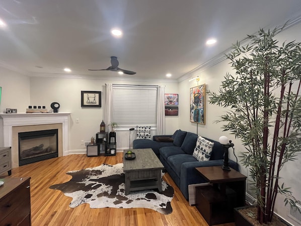 A living room with a fireplace, a sofa, a coffee table, and a large plant.