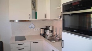 Eine kompakte Küche mit Backofen, Kaffeemaschine und Spüle.
