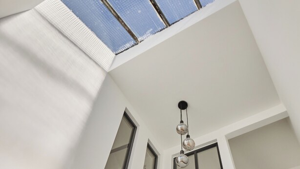 Un intérieur moderne avec un plafond en pente, une lucarne et un luminaire suspendu.