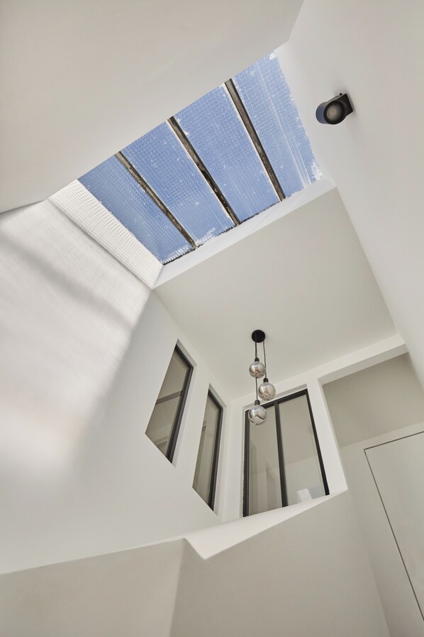 A modern interior with a sloped ceiling, skylight, and a hanging light fixture. - Apartment located in the heart of Aix-en-Provence (Saint-Antonin-sur-Bayon)