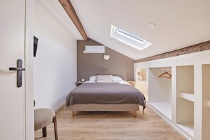 A bedroom with a sloped ceiling, a bed, a bedside table, a hanging light, and a wardrobe. - Apartment located in the heart of Aix-en-Provence (Saint-Antonin-sur-Bayon)