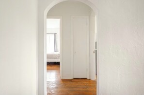 Ein Flur mit Holzboden, weißen Wänden und einer geschlossenen Tür.