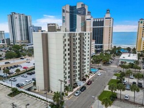 A high-rise hotel with multiple floors, a parking lot, and a view of the ocean. - Cozy 1-br condo 1 block from beach with AC and balcony in marvelous Myrtle Beach (Myrtle Beach)