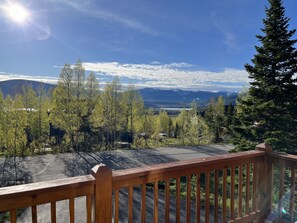 A wooden deck with a view of a mountainous landscape, trees, and a road. - Colorado Mountain Home Available for Monthly Summer Rental (Silverthorne)