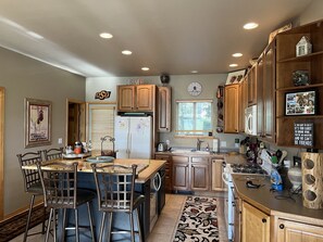 A kitchen with wooden cabinets, a refrigerator, a sink, and a dining area with chairs. - Colorado Mountain Home Available for Monthly Summer Rental (Silverthorne)