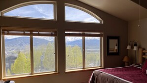 Ein Schlafzimmer mit großen Fenstern, einem Bett, einem Heizgerät und einem Deckenventilator.