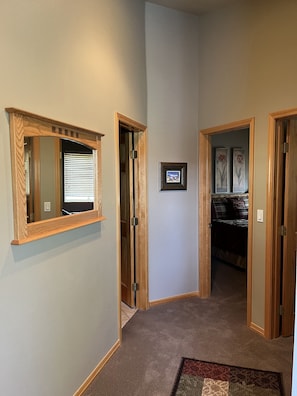A hallway with wooden doors, a framed picture on the wall, and a carpeted floor. - Colorado Mountain Home Available for Monthly Summer Rental (Silverthorne)