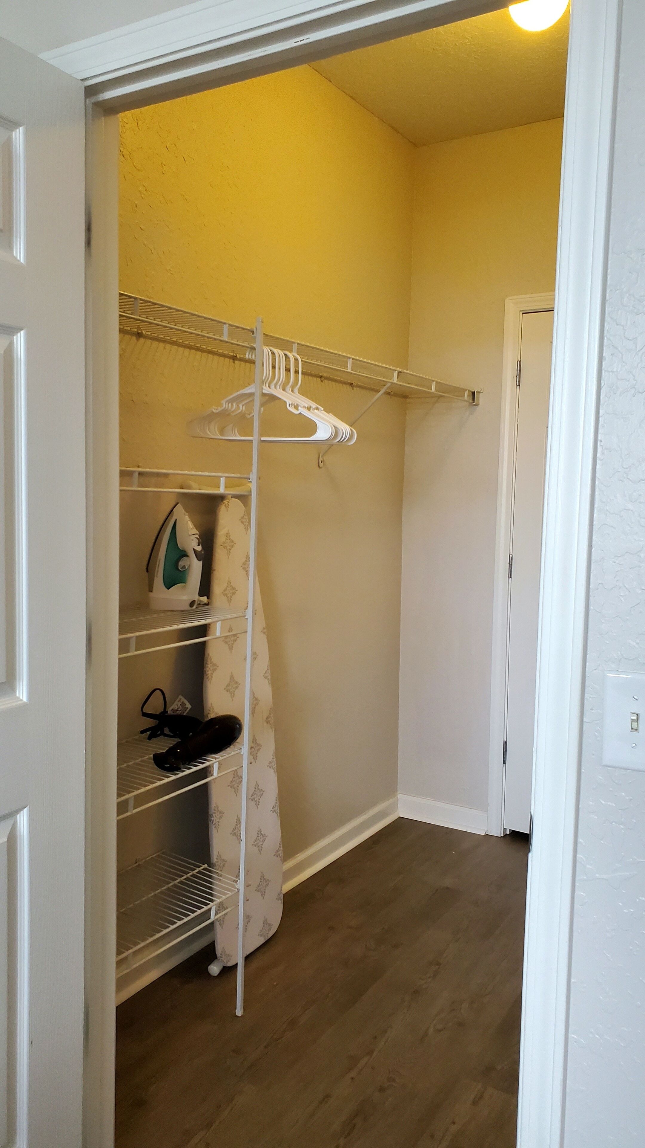 Um closet amplo com cabideiro, prateleiras e espaço para sapatos.