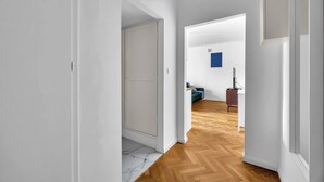 Un corridoio che conduce a una zona giorno con pavimento in legno, una porta e una decorazione blu al muro.