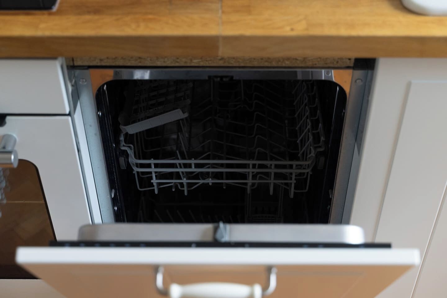 An open dishwasher with a rack inside.