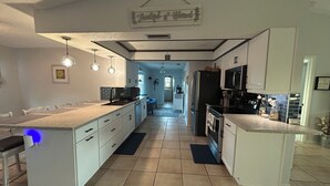 Una cocina moderna con armarios blancos, una isla central e iluminación colgante.