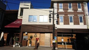 A hotel with a modern facade, a wooden entrance, and a red awning. - Onomichi Minato Hotel (Onomichi)