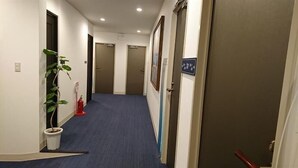 A hallway with a blue carpet, a potted plant, and doors leading to rooms. - Onomichi Minato Hotel (Onomichi)