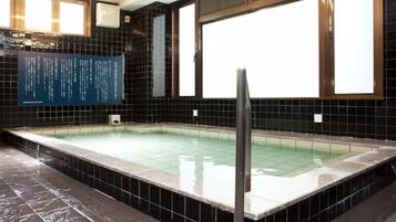 A rectangular indoor pool with black tiled walls and a tiled floor.
