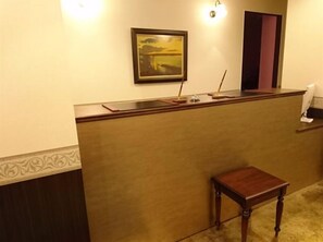 A reception desk with a framed picture, a small table, and a door. - Onomichi Minato Hotel (Onomichi)