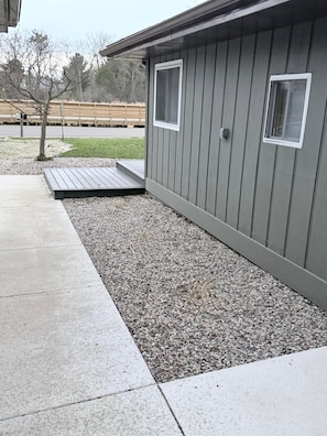 A building with a gravel driveway, a wooden deck, and a small window. - Fantastic 3-bedroom house with AC in enchanting Windsor (Windsor)