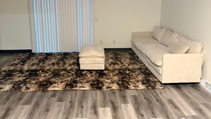Una sala de estar con un sofá, una alfombra y una ventana con persianas.
