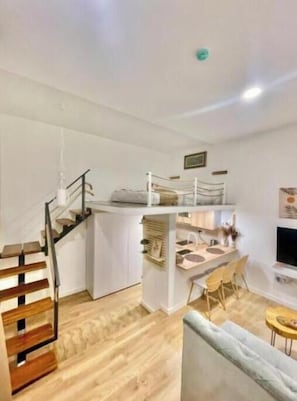 Une cuisine moderne dotée d’un îlot central intégré, un coin repas avec une table et des chaises, et un escalier menant à un autre niveau.