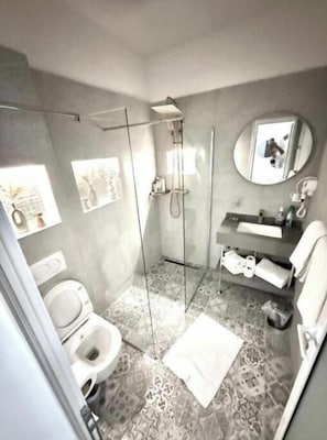 Une salle de bain moderne avec une douche à parois de verre, des toilettes, un lavabo avec un miroir et un carrelage décoratif.