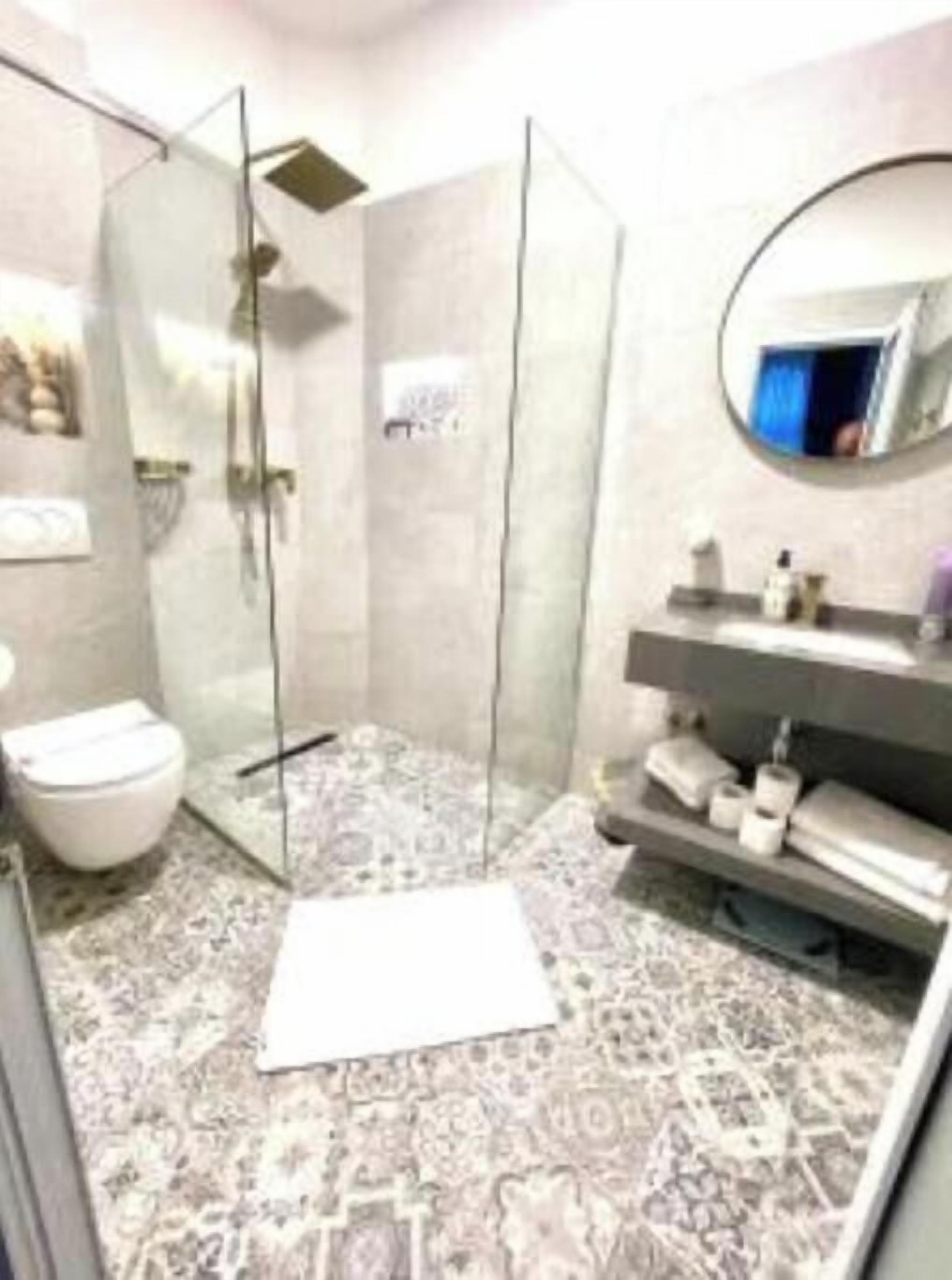 A modern bathroom with a glass shower enclosure, a toilet, and a vanity with a mirror.