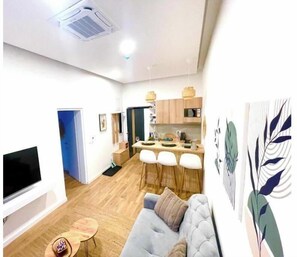 Ein modernes Wohnzimmer mit Sofa, Fernseher und Essbereich mit Stühlen und Tisch.