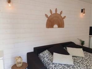 A bed with floral bedding, a woven wall decoration, and two wall-mounted lights. - 🌞 Le Drakkar - Studio - Parking Clim Wifi - La Grande Motte / Le Point Zéro 🌞 (La Grande-Motte)