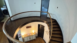 Un escalier en colimaçon avec des rampes en bois et un petit espace détente au bas.