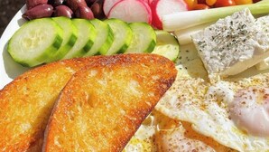 A plate of food with toast, eggs, cheese, and various vegetables.