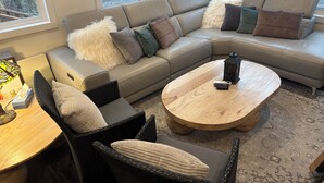 Una sala moderna con un sofá modular, una mesa de centro redonda y una silla de mimbre.