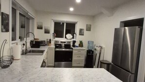 Una cocina moderna con encimera de mármol, electrodomésticos de acero inoxidable y un refrigerador grande.