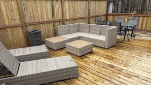 Una terraza de madera con mobiliario de mimbre, incluyendo sofás y sillones.
