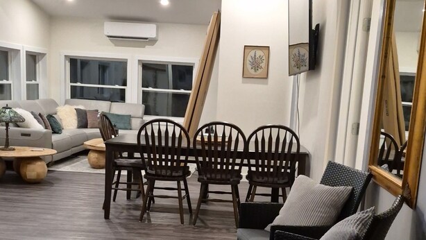 Una sala de estar con sofá, mesa de comedor, sillas y un espejo grande.