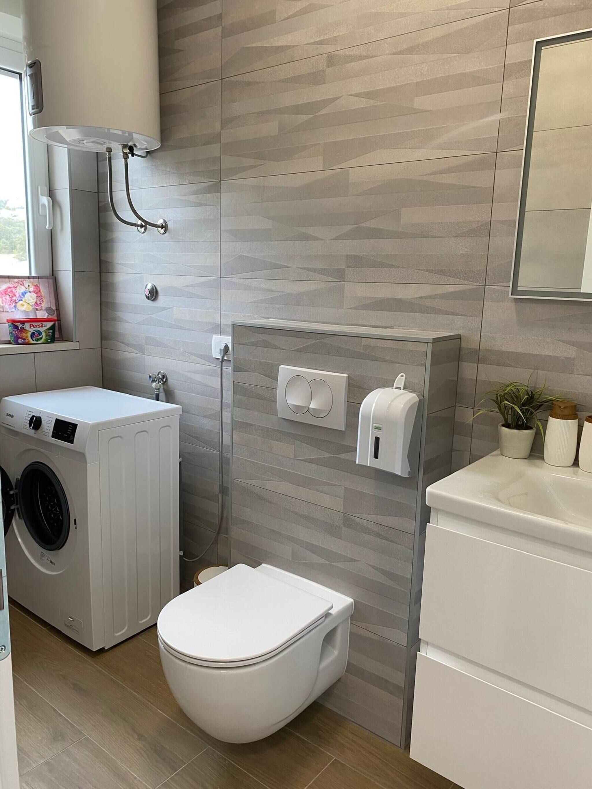 Ein modernes Badezimmer mit Waschmaschine, Toilette und einem Händetrockner.