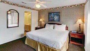 Una camera d'albergo con un letto, due comodini, una ventola a soffitto, un quadro e uno specchio.