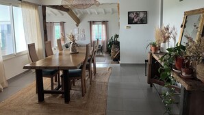 Zona pranzo con tavolo in legno, sedie, lampadario e piante in vaso.