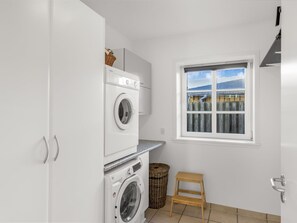 Ein Waschraum mit gestapelten Waschmaschinen und Trocknern, ein Fenster mit Aussicht und ein kleiner Holzschemel.