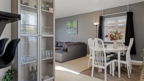 A modern living room with a sofa, dining table with chairs, a glass cabinet with items, and a painting on the wall. - "Bisera" - 3km from the sea by Interhome (Rødby)