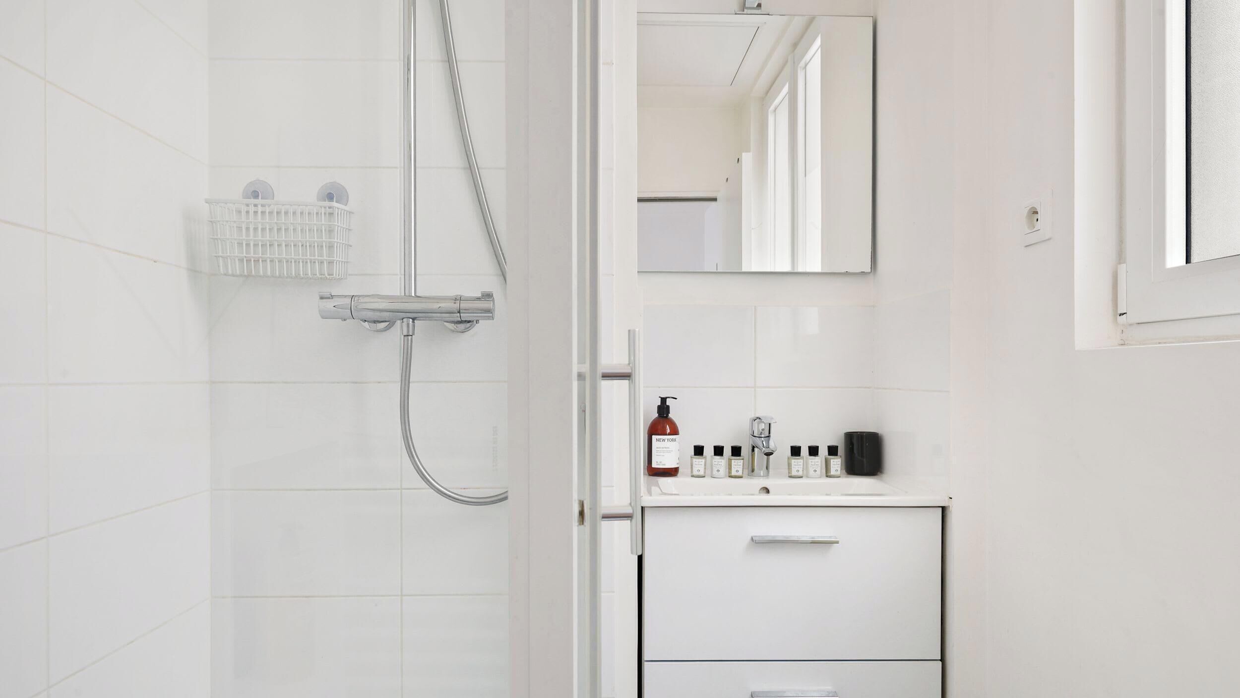 A modern bathroom with a shower, a mirror, and a vanity with toiletries.