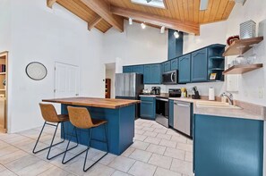 Una cucina moderna con mobili blu, un'isola centrale con sgabelli da bar e un forno a microonde integrato.