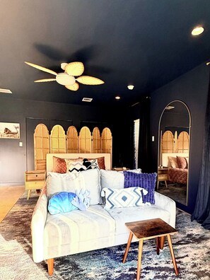 A modern bedroom with a bed, bedside tables, a ceiling fan, and a large mirror. - MerManor - An Iconic Merman Pool Oasis (Fort Lauderdale)