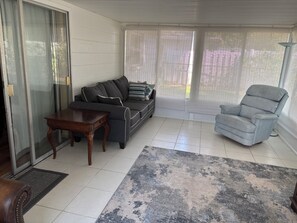 Ein Wohnzimmer mit Sofa, Sessel, Couchtisch und einem gemusterten Teppich.