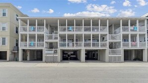 A multi-story building with balconies, a covered entrance, and a parking area. - Beach Block with ocean views in downtown Tybee Island (Tybee Island)