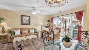 A living room with a sofa, coffee table, and chairs, a chandelier, and a view of the outdoors. - Beach Block with ocean views in downtown Tybee Island (Tybee Island)